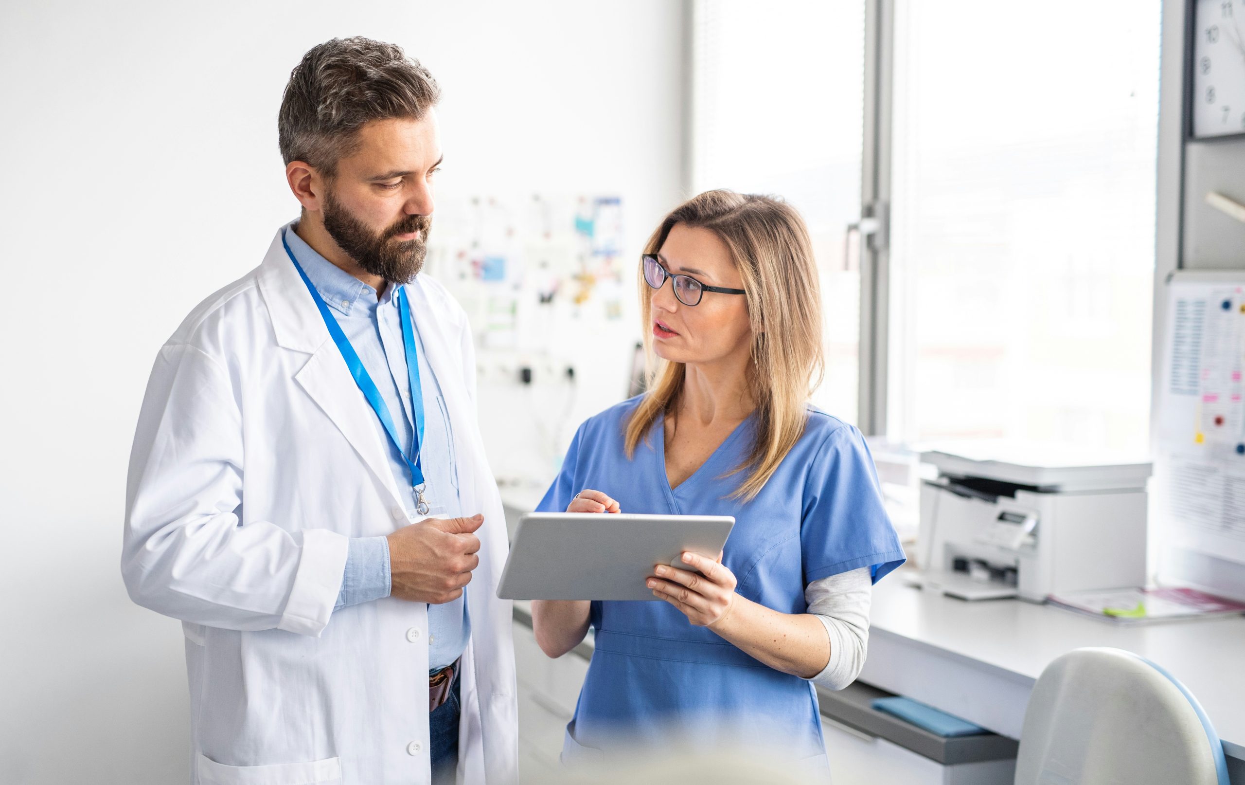 Medical professionals discussing a case using a tablet in a clinical setting