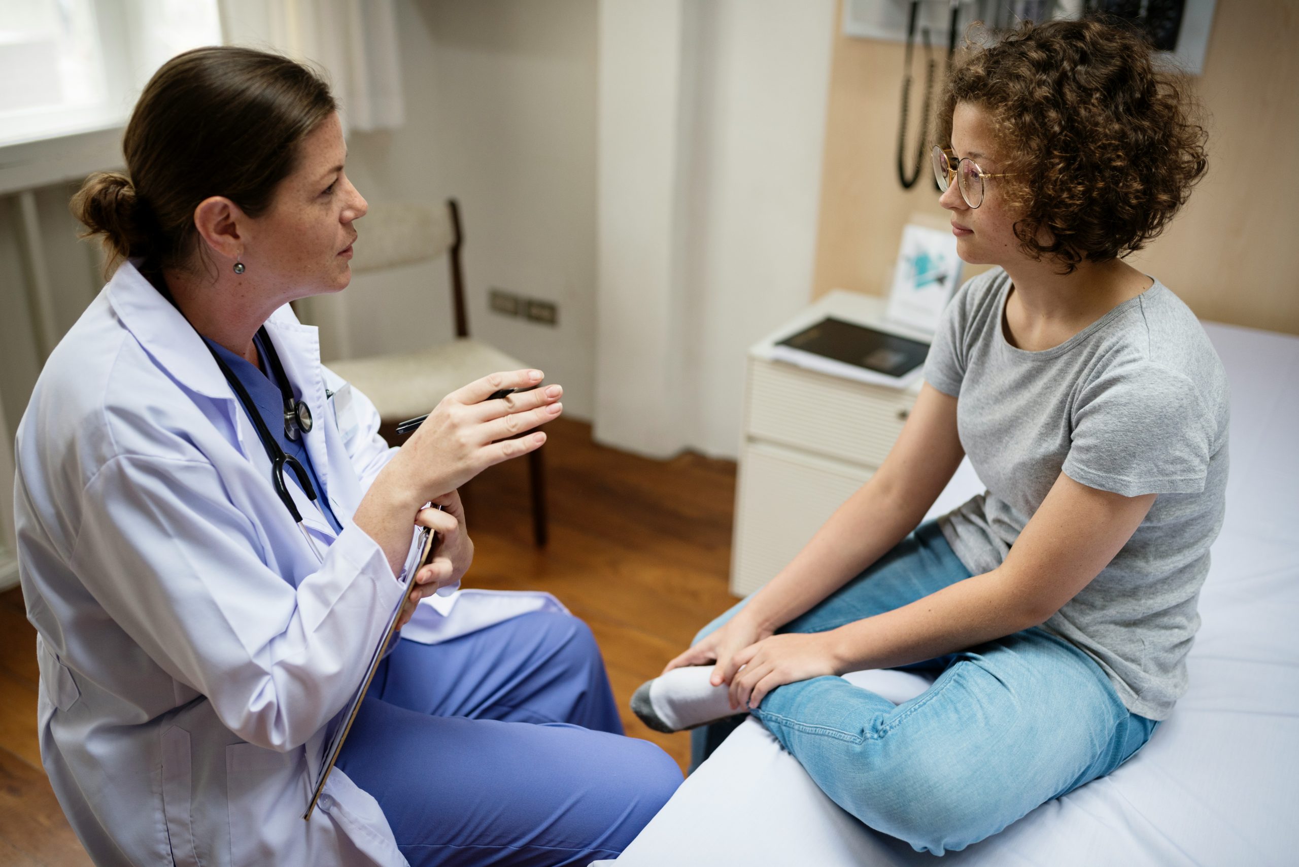 Doctor talking with teenage patient during medical consultation